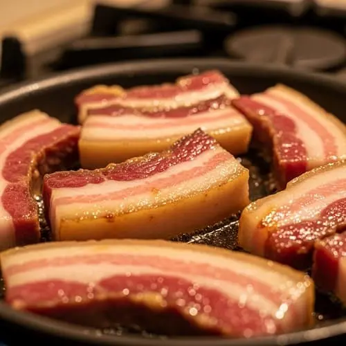 Spaghetti Carbonara original: Rezept ohne Sahne 3 Rinderbacon wird in der Pfanne langsam ausgelassen, bis er goldbraun und knusprig ist