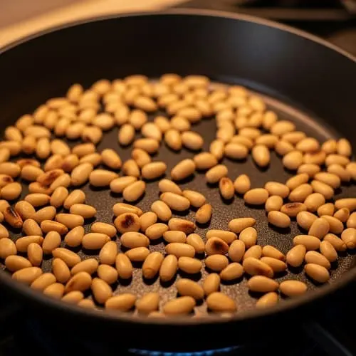 Pinienkerne werden in einer Pfanne ohne Fett goldbraun geröstet